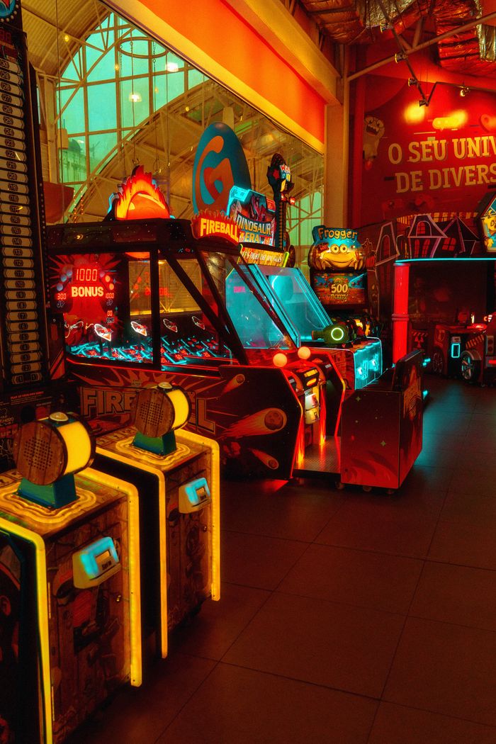 about-us-01 Colorful arcade room with glowing neon lights and game machines at night.