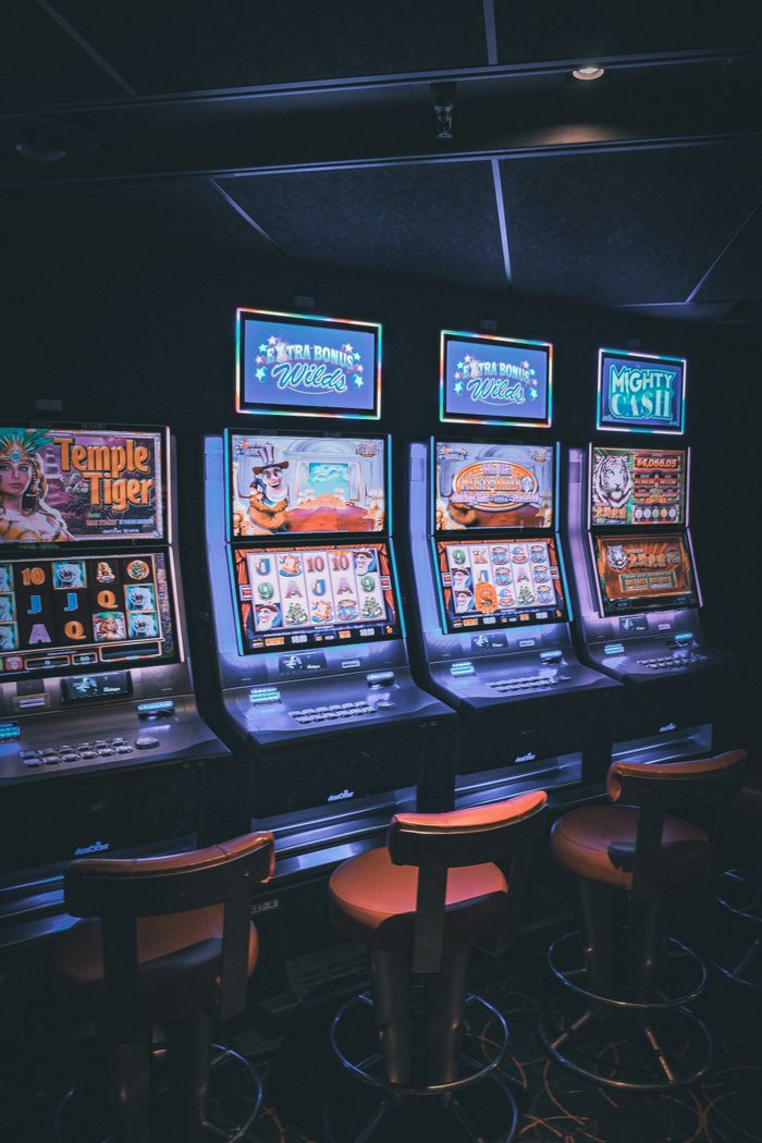about-us-02 Row of illuminated slot machines in a dimly lit, empty casino area.