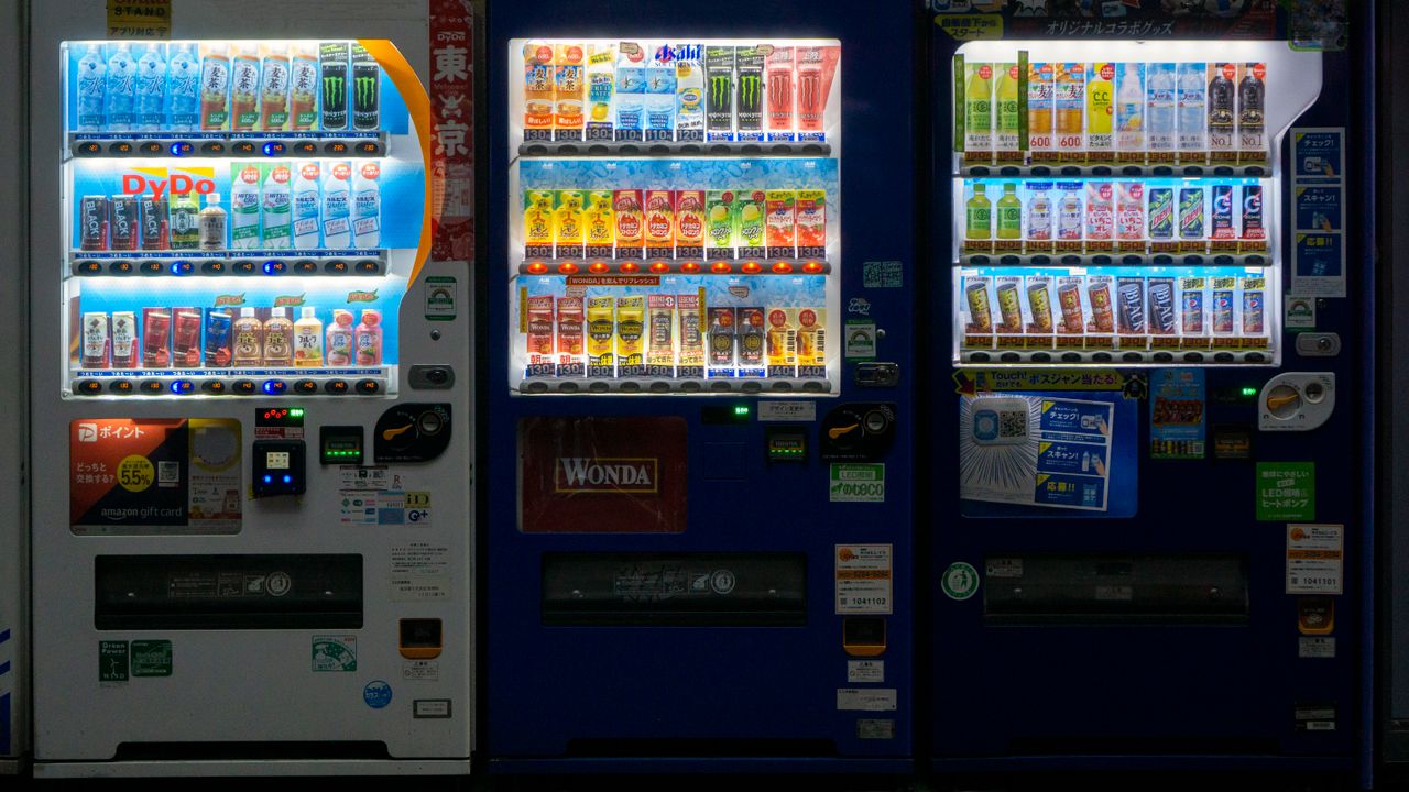 services-03 Three vending machines in Taito City, Tokyo at night showcasing a variety of drinks.