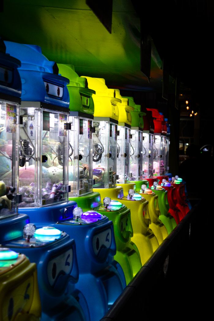 about-us-02 Colorful arcade claw machines illuminated at night, creating a fun and lively atmosphere.
