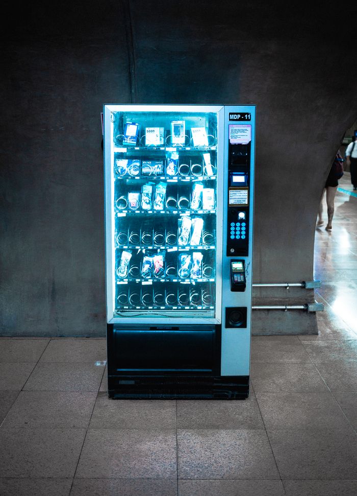 services-04 A glowing vending machine stocked with various products in a dimly lit corridor.