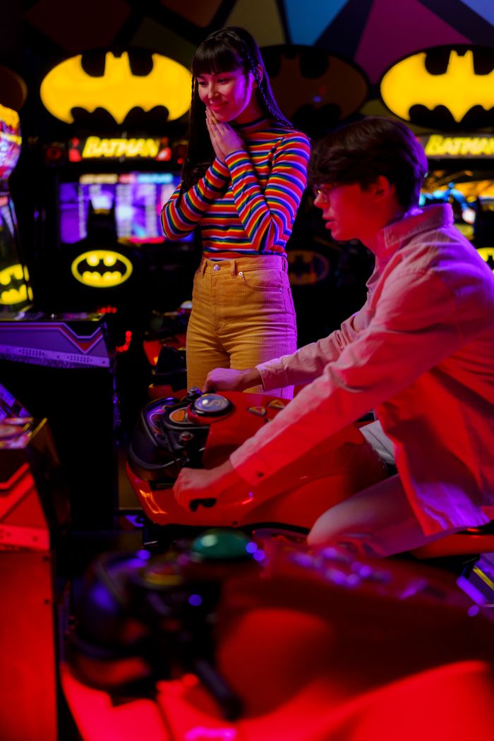 services-01 A couple playing a motorcycle racing video game at an amusement arcade.